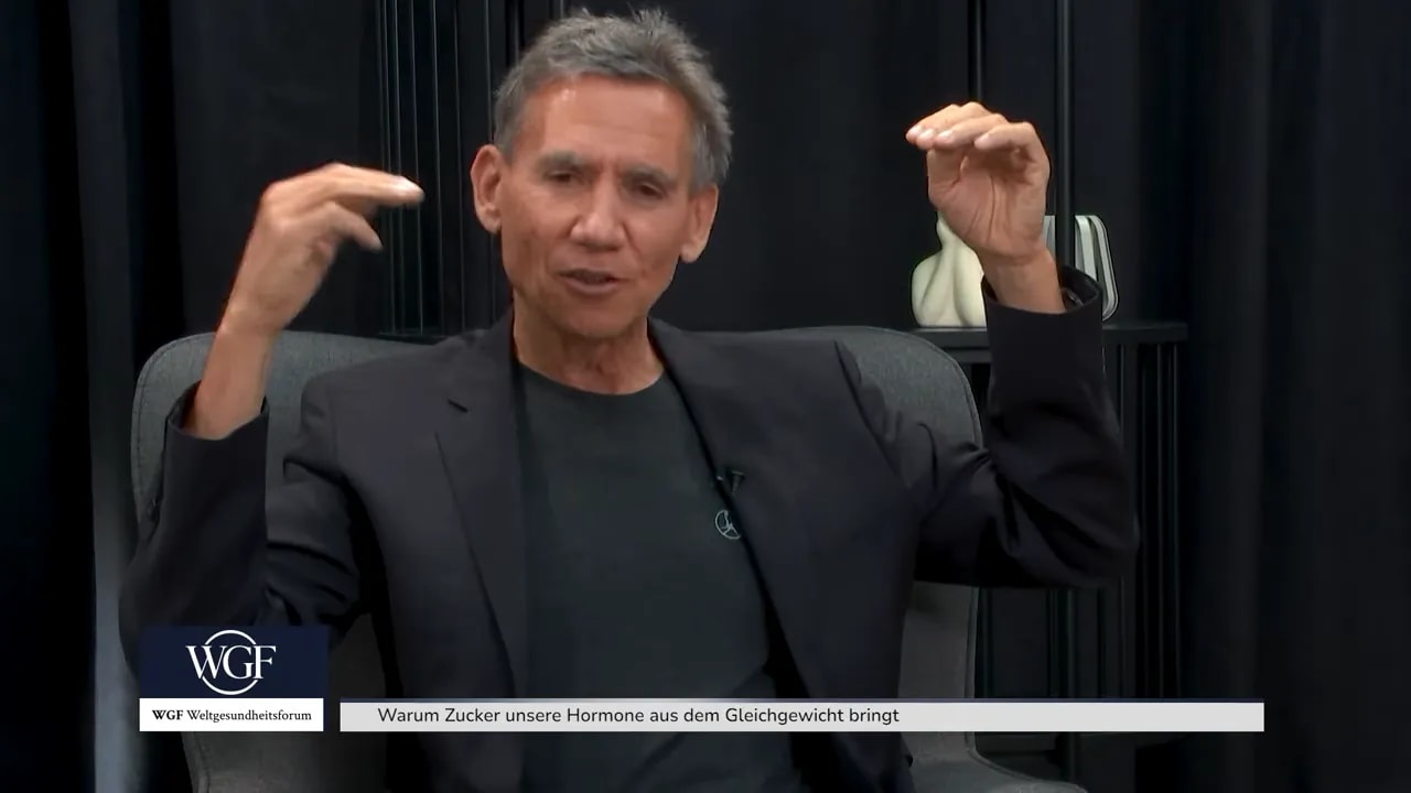 Dr. Kurt Mosetter sitzt im Sessel und hält beide Hände auf Kopfhöhe