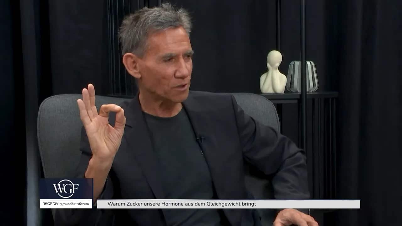 Dr. Kurt Mosetter hebt beide Hände über den Kopf während er spricht